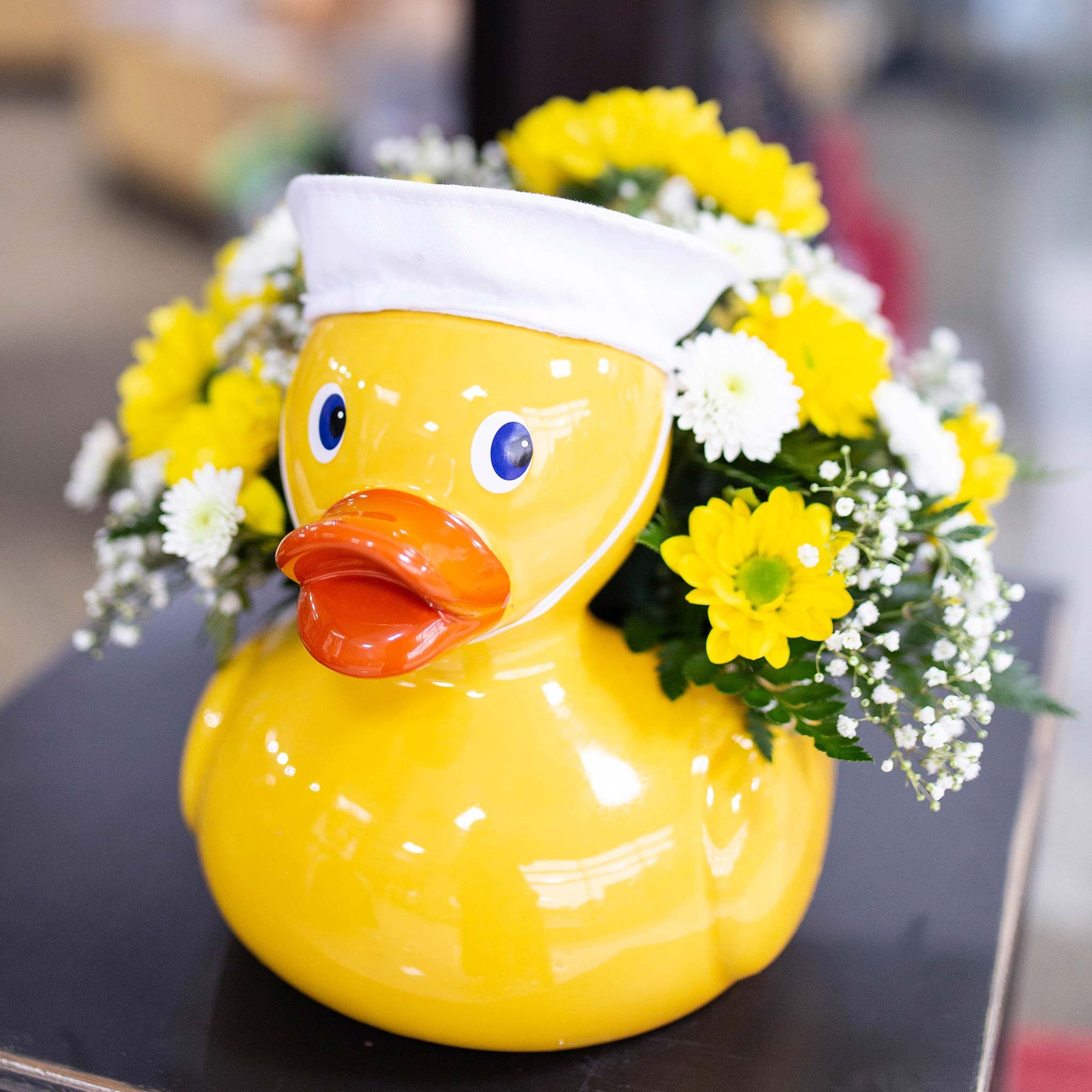 Yellow and white flowers in a yellow duck vase
