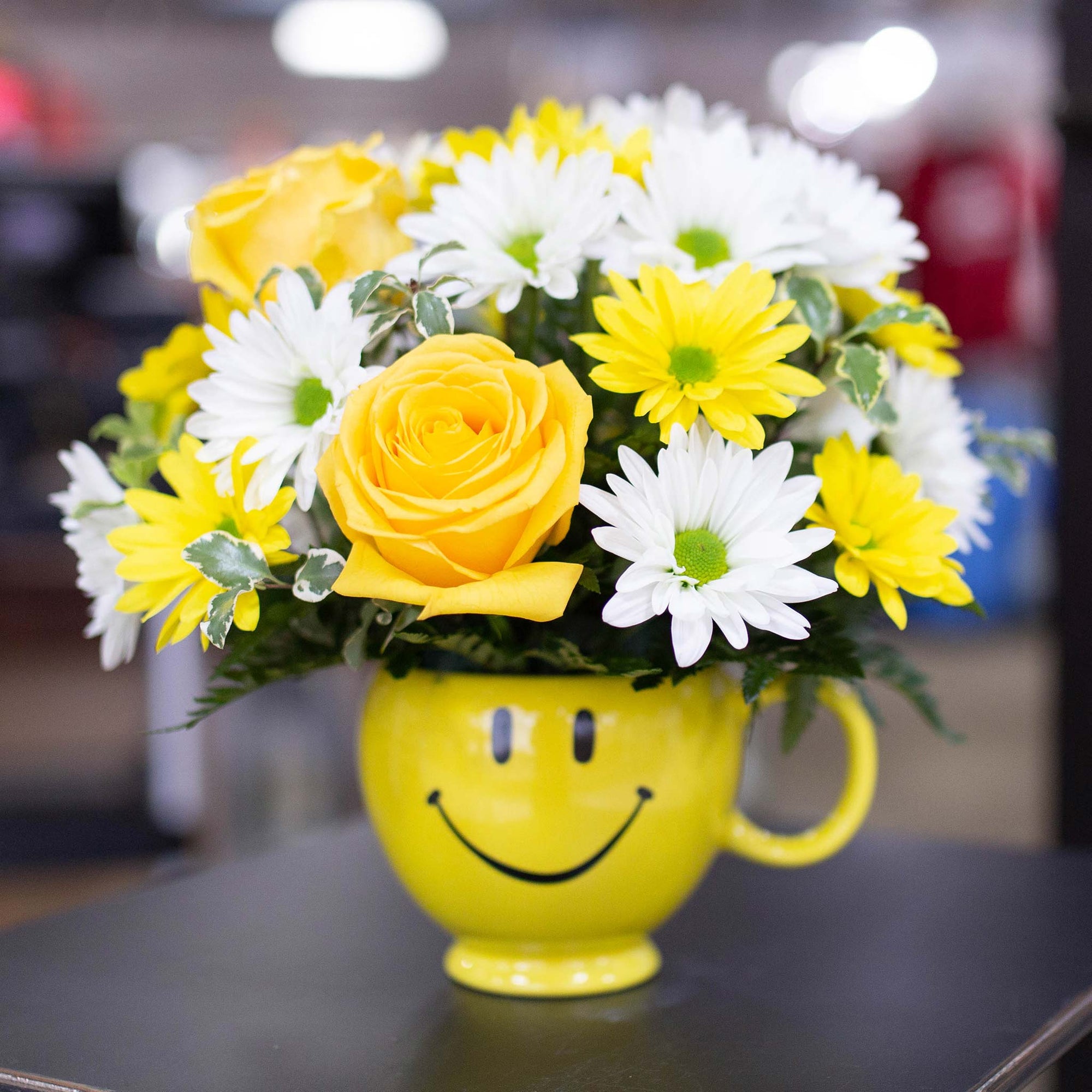 Yellow and white flowers in a smiley face mug